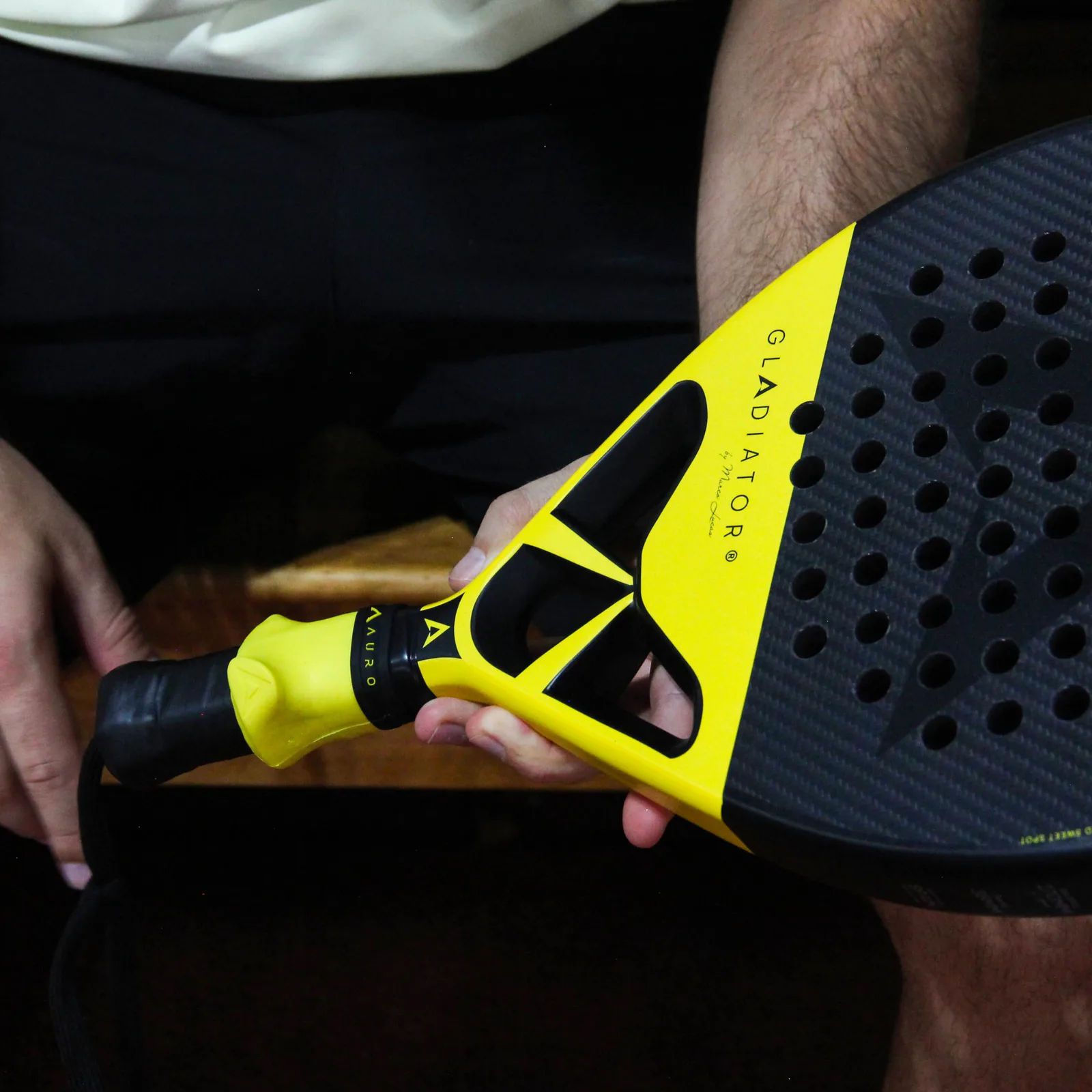 Pala Auro Gladiator sujeta con una mano, con el Auro Grip amarillo colocado en el mango